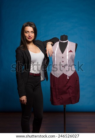 Woman with  hand on mannequin shoulder, on blue background