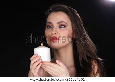 Portrait of a woman with a candle. Black background. Studio shot.