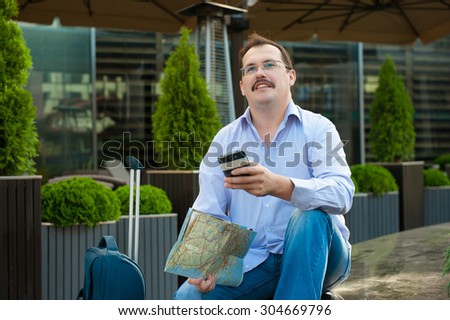 Traveler with mobile phone and city plan sitting outdoors.
