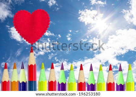 Row of colorful pencils. Red pencil out of line and drawn heart above.