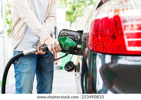 Lower body of a asian woman refueling her car