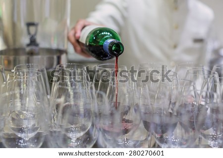 Waiter pouring a bottle of red wine in a bar