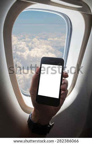 hand holding mobile phone in the airplane