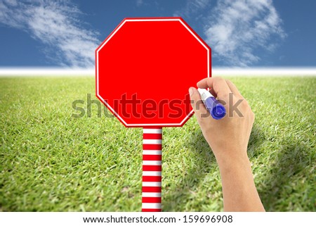 Hand and red sign on lawn in free space on label if you can put words to it.