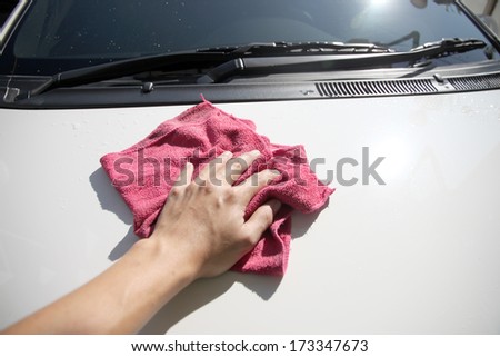 Hand cleaning white car in house.
