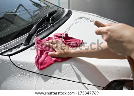 White car washing with fabric and Water hose in house.