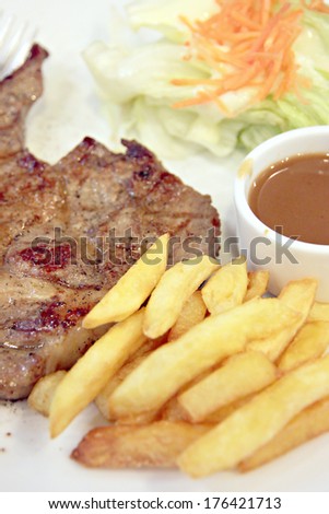 Pork steak with French Fries in dish.