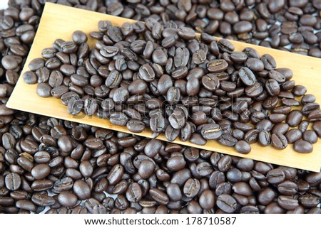 Coffee beans in bamboo dish on white background.