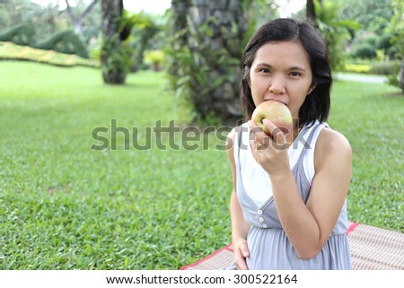 Thai pregnant mom to eat apple in the garden for healthy full strength.