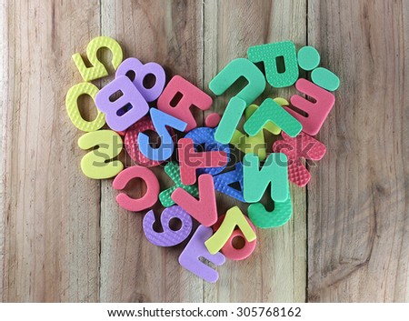 The numbers and letters arranged in a shape heart on wood background.