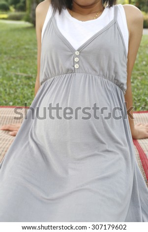 Pregnant women at the age pregnancy of four months relaxing in the garden.