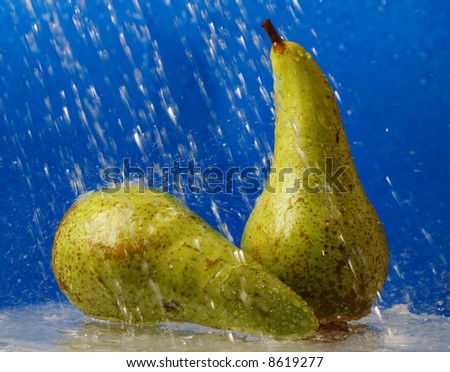Two pears under water streams over blue background.