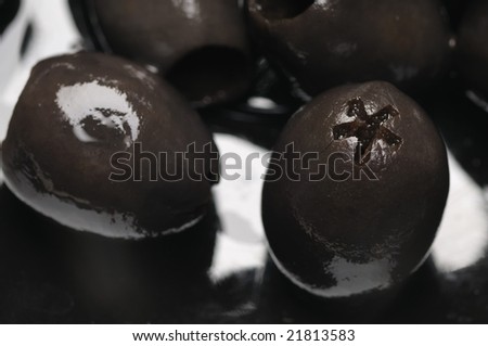 Black olives without the stone on the black plate. Narrow depth of field.