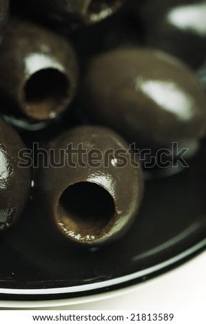 Black olives without the stone on the black plate. Narrow depth of field.
