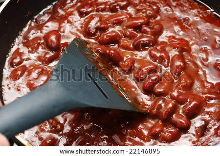 Red beans in the chili sauce fry on the skillet. Narrow depth of field.