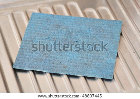 Dirty blue sponge on the metal sink.