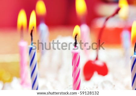 Candles on the birthday cake. Narrow depth of field. Close-up. Orange tint.