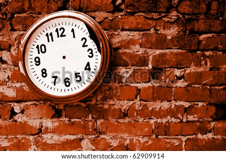 Broken clock without hands on the brick wall.