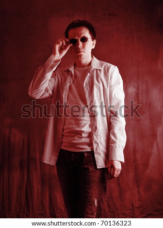 Man in the sunglasses posing on the grey background. Red tint.
