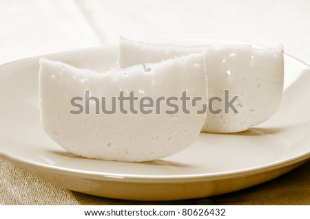 Two thin pieces of cheese on the yellow plate. Sepia tint.
