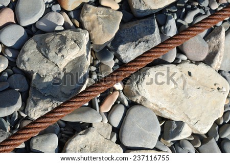 Old and rusty metal rope on rocks.
