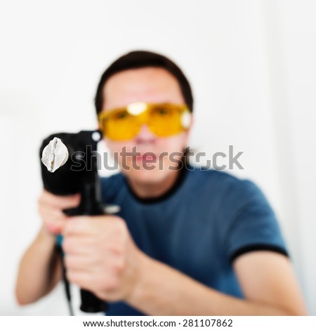 Man with hammer drill in hands. Only drill bit in focus.