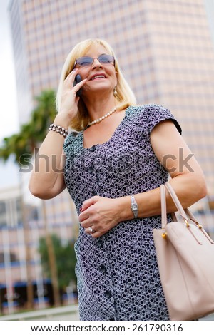 Close Up portrait happy smiling attractive business woman in glasses 60 years in the downtown talking with mobile phone, Lifestyle woman on phone, Business concept woman calling on the phone in street