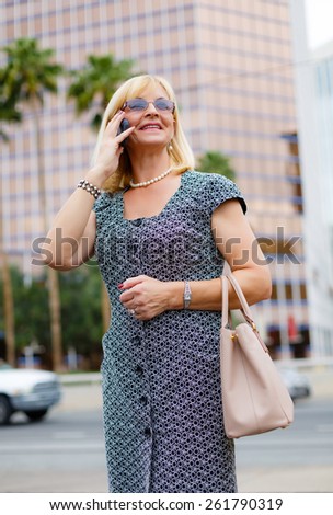 Close Up portrait happy smiling attractive business woman in glasses 60 years in the downtown talking with mobile phone, Lifestyle woman on phone, business woman calling on the phone in street