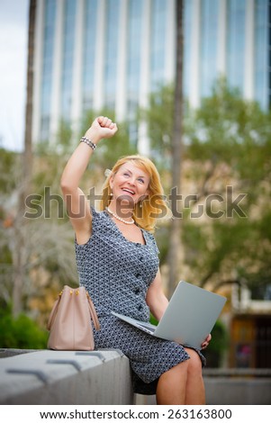 Close Up portrait, Happy and Smiling old senior business woman 60-65 years, using laptop computer in New York city park, looking to up, with gesture on face, emotion raised hand up