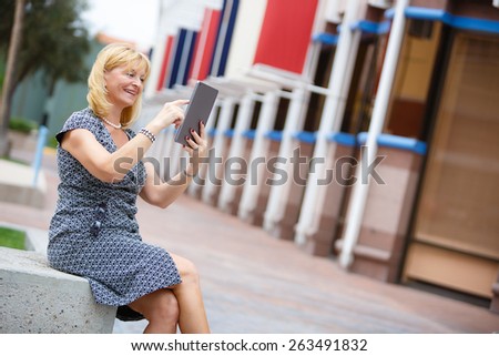 Happy smiling rich old business woman 60 years in New York City using ipad tablet pc computer reading ebook