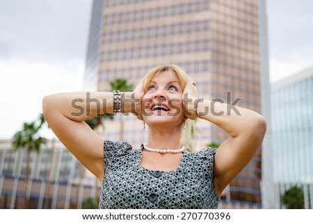 Happy old senior blonde woman 60-65 years with white teeth on city background