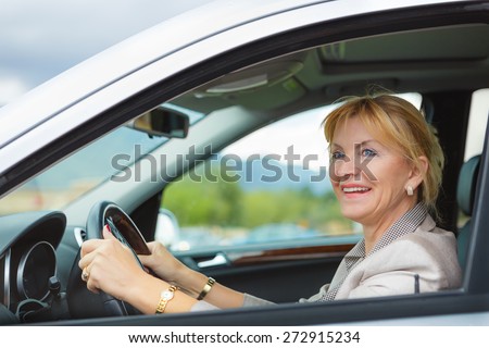 Beautiful smiling elderly woman 55-60 years with white teeth in suit at the whee, Driving a Car Through the mountains