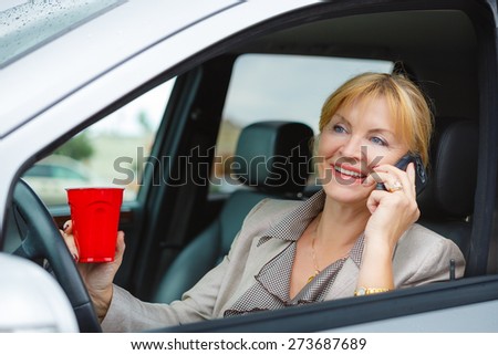 Beautiful Smiling and happy old senior business women 60-65 years, driver is safely talking by mobile phone in a car
