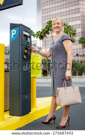 Happy and smile senior aged business woman 55-65 years with a lovely charming smile paying for parking in the street. Positive human emotion, facial expression
