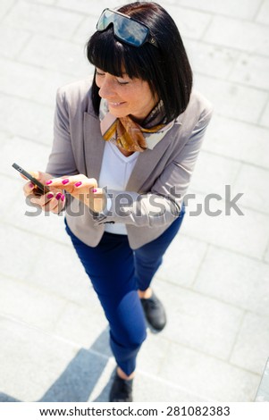 Happy, cheerful, brunette woman, excited by what she sees on cell phone, Facial expression, reaction. Business woman sending text message from her mobile