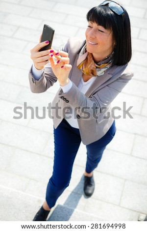 Portrait of Happy, cheerful and smile, brunette business woman, excited by what she sees on cell phone, Facial expression, reaction. Business woman sending text message from her mobile
