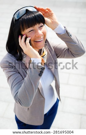 Smile Brunette business woman in street speaks by cell mobile phone and put hand in pocket with sunglasses on head, Positive human emotion, facial expression, spring mood