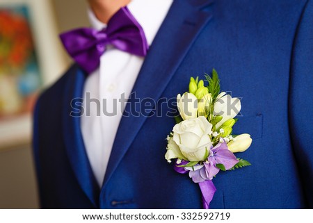 Close-up of a groom in the wedding blue suit with flowers boutonniere on his lapel and butterfly