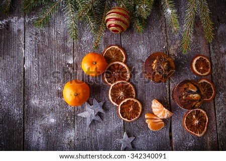 Xmas composition with holiday decoration - Homemade christmas cupcakes, sliced dried oranges on wooden background with spruce twigs and christmas toy. Christmas card. Space for text