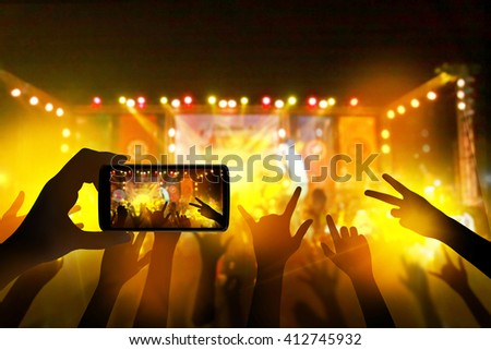 Hand with a smartphone records live music festival, live concert, music festival, happy youth, luxury party, landscape exterior.