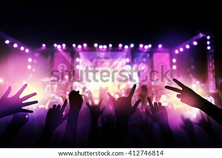 Audience with hands raised at a music festival and lights streaming down from above the stage. live concert, music festival, happy youth, luxury party, landscape exterior.