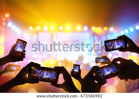 Silhouette of hands using camera phone to take pictures and videos at live concert,  smartphone records live music festival, Take photo in front concert stage, happy youth, luxury party.