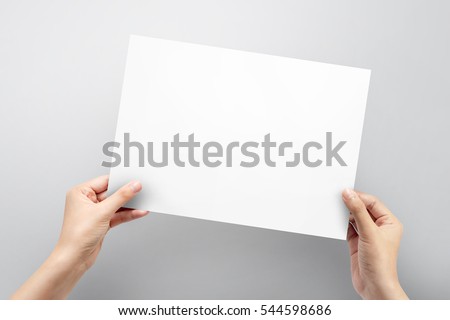 Close up hands holding paper blank a4 size for letter paper on a grey background.
