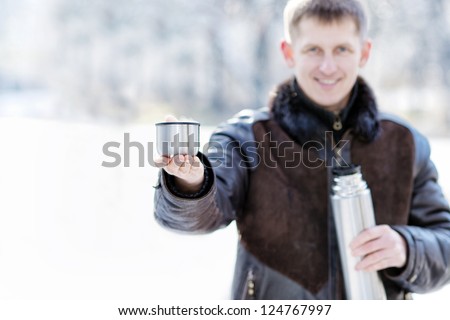 handsome young man drinks hot tea in the winter outdoors, outdoor