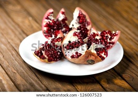 Pomegranate fruit on the table, sliced. pomegranate on a plate, peel a pomegranate,
