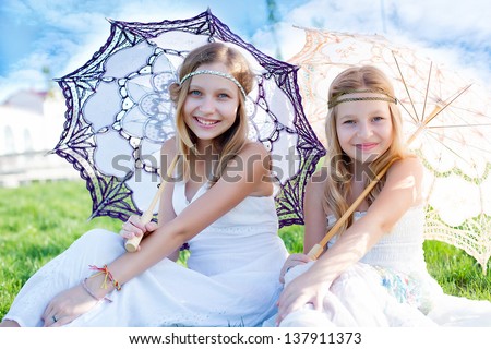 Two girls sitting on the grass with bare feet. sisters sitting on the grass under the umbrellas
