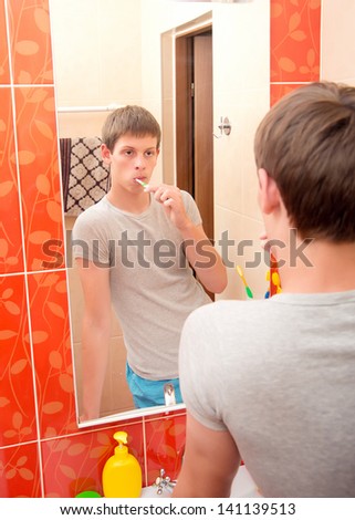 A man brushes his teeth in the bathroom..washing hands in bathroom.Wash basin with mixer tap and towels