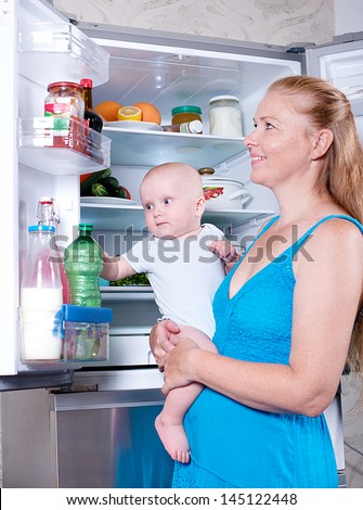 Young mother with a child takes food out of the fridge. Storing food in the refrigerator
