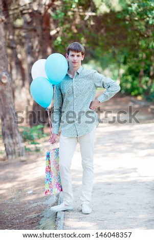 Young handsome man with gift and balloons. Gift Delivery