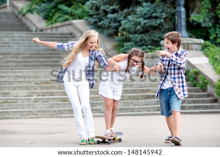 Children learn to ride a skateboard. Children ride on a skateboard mom. Young beautiful mother goes on a skateboard.
